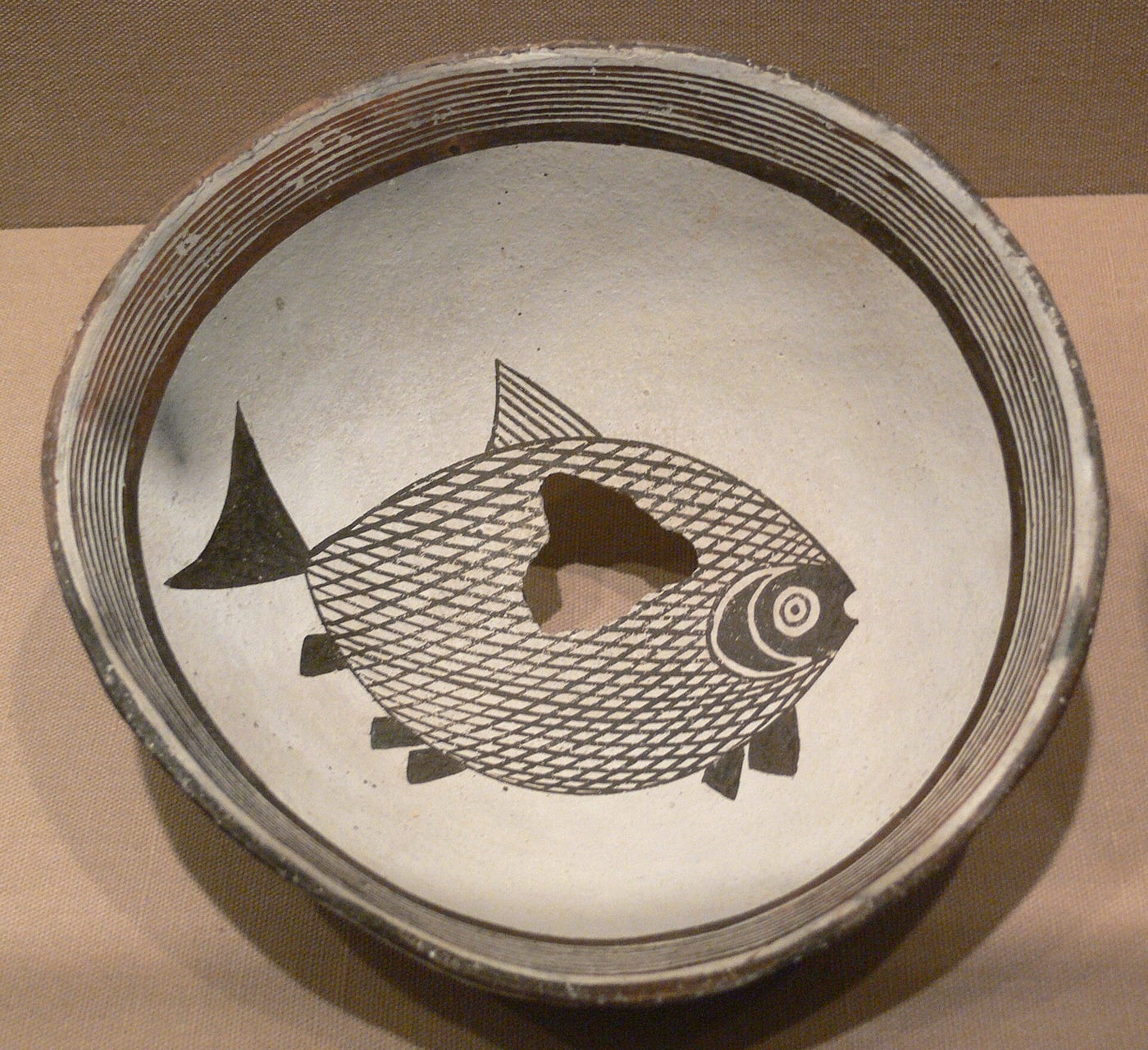 Mimbres culture ceramic bowl depicting an otter with a fish in its mouth, c. 900–1150 CE, from the American Southwest, showing the distinctive black-on-white Mimbres ceramic style.