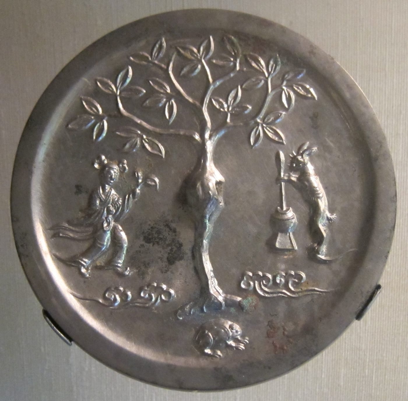 Tang dynasty Chinese bronze mirror back showing the moon goddess Chang'e with the moon-rabbit (yutu) pounding the elixir of immortality beneath the cassia tree.
